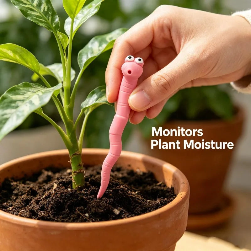 Cute Worm Plant Ornaments: a hand placing a pink decorative worm in soil beside a leafy plant in a terracotta pot.