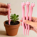 Cute Worm Plant Ornaments held in hand beside a terracotta pot, showing pink segmented bodies and pointed ends.