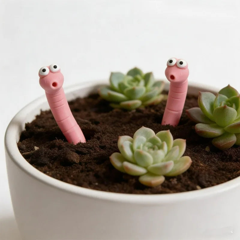 Cute Worm Plant Ornaments: two wide-eyed pink worms nestled among succulents in a shallow white planter.