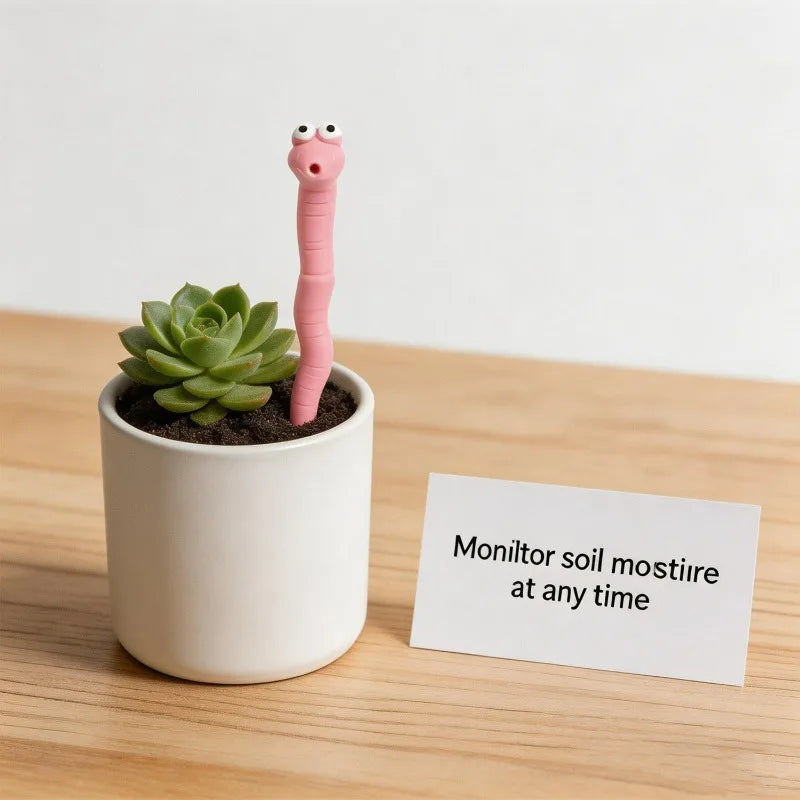 Cute Worm Plant Ornaments: pink worm beside a succulent in a white pot on a wooden tabletop, with a supplier sign.