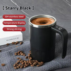 Digital Self-Stirring Mug black mug with a swirling coffee drink, handle display and coffee beans on gray fabric.