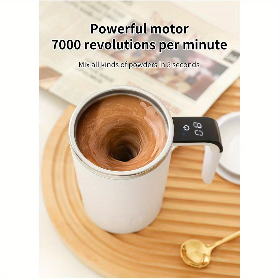 Digital Self-Stirring Mug white mug and stirring feature graphic on a wooden tray beside a gold-colored spoon.