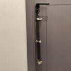 Black nylon dog potty training bells hanging from a dark door handle