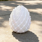 Dragon Egg Fidget Toy in white standing outdoors with the segmented spiral pattern visible