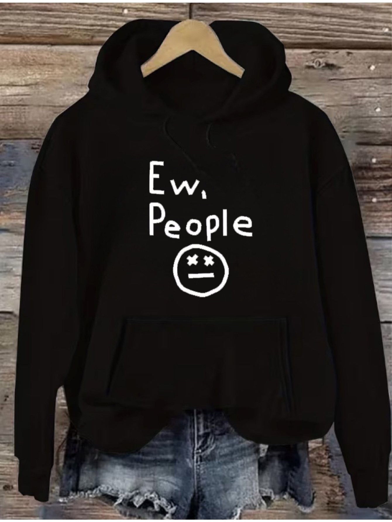 "Ew, People" Hoodie in black hanging above denim shorts with the white graphic centered