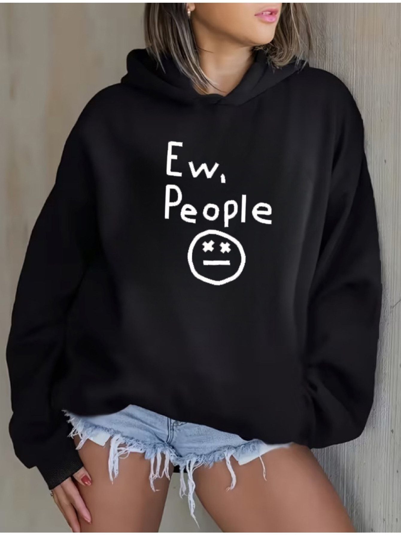 "Ew, People" Hoodie in black modeled against a neutral wall with the graphic fully visible