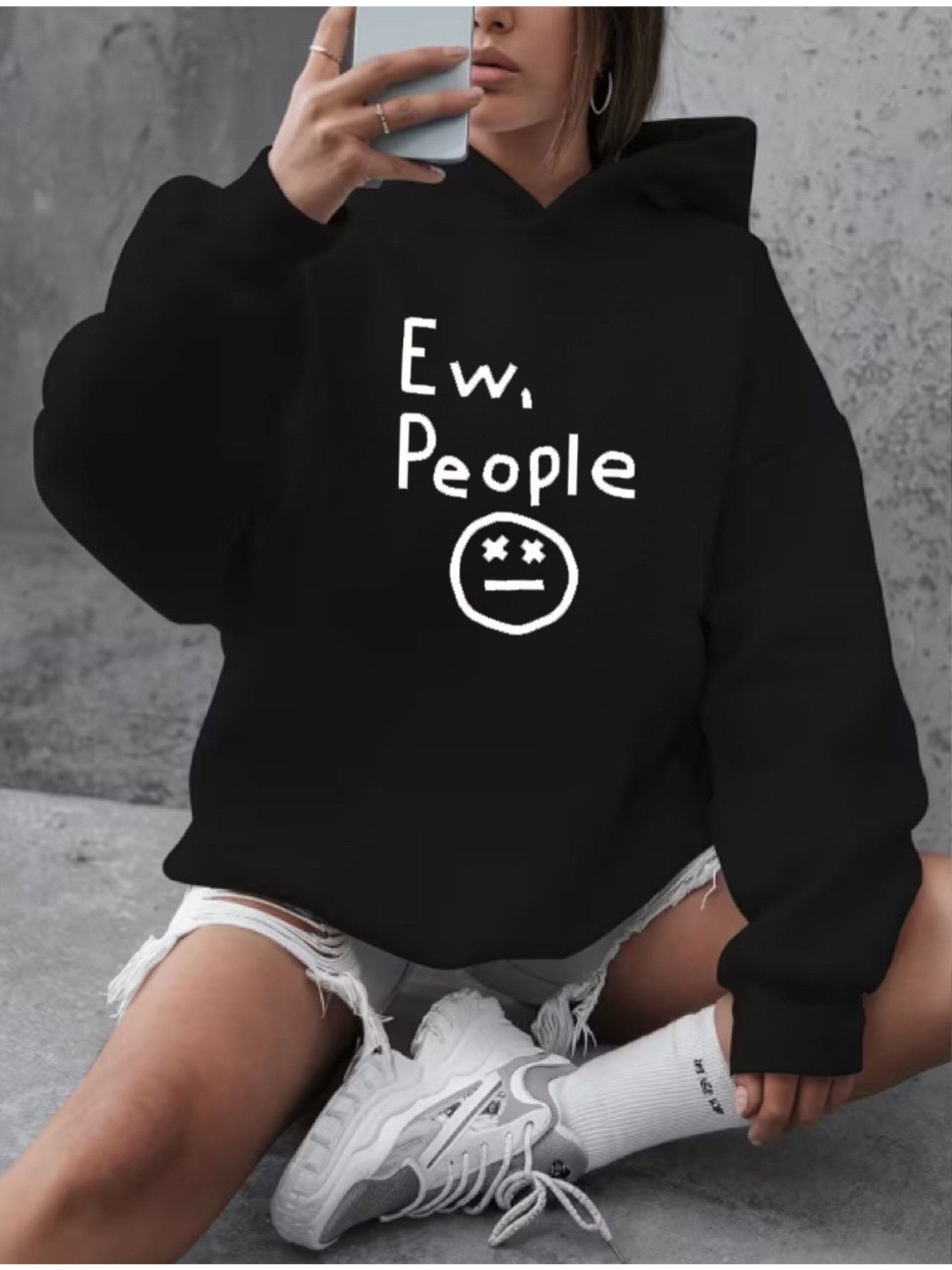 "Ew, People" Hoodie in black worn by a seated model in a casual everyday setting