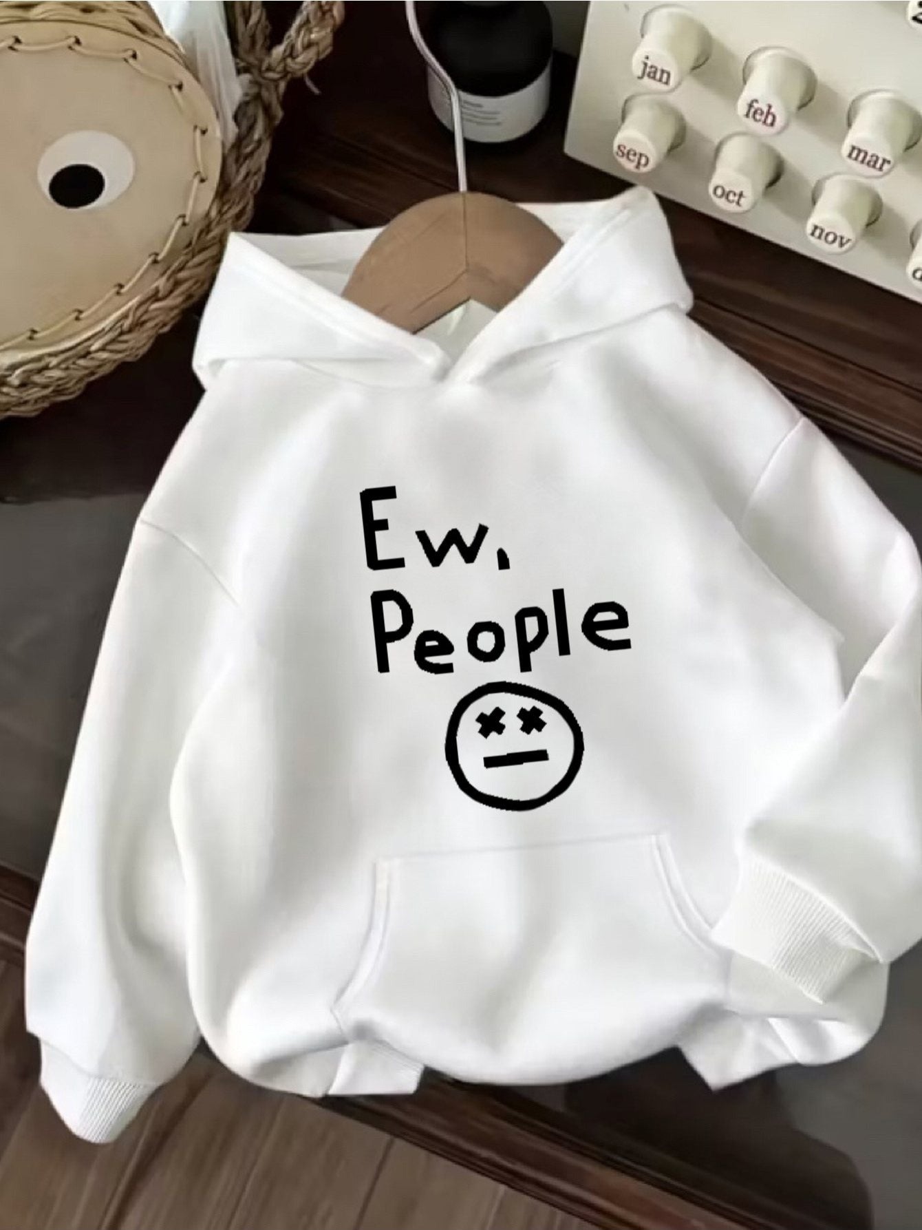"Ew, People" Hoodie in white arranged in a flat lay with the graphic centered