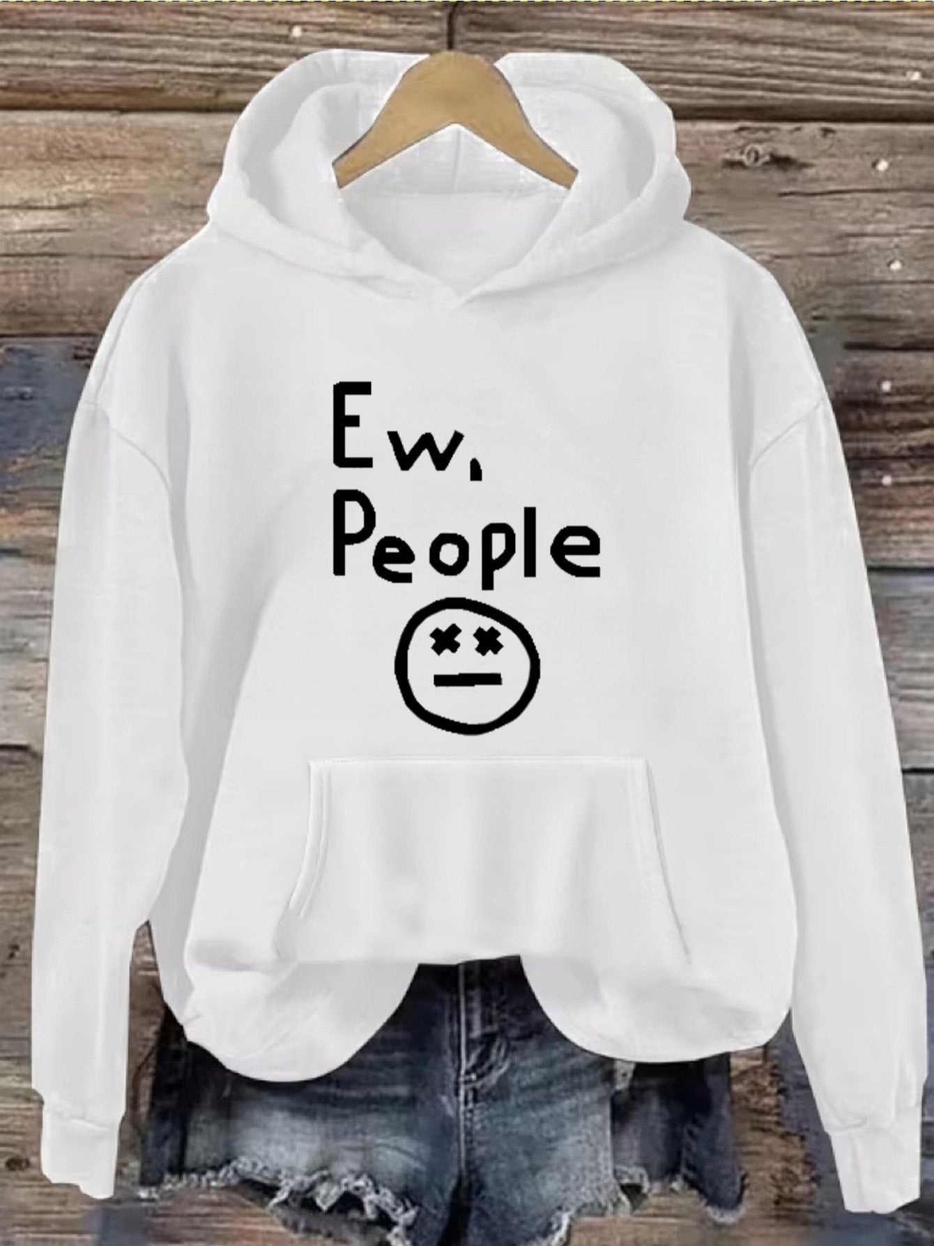 "Ew, People" Hoodie in white hanging above denim shorts for a casual outfit view