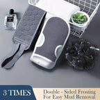Gray back strap and bath mitt with a black mesh loofah arranged beside a towel and plant
