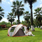Family Pop-Up Tent in brown and gray with a camper seated at the doorway beneath palm trees.