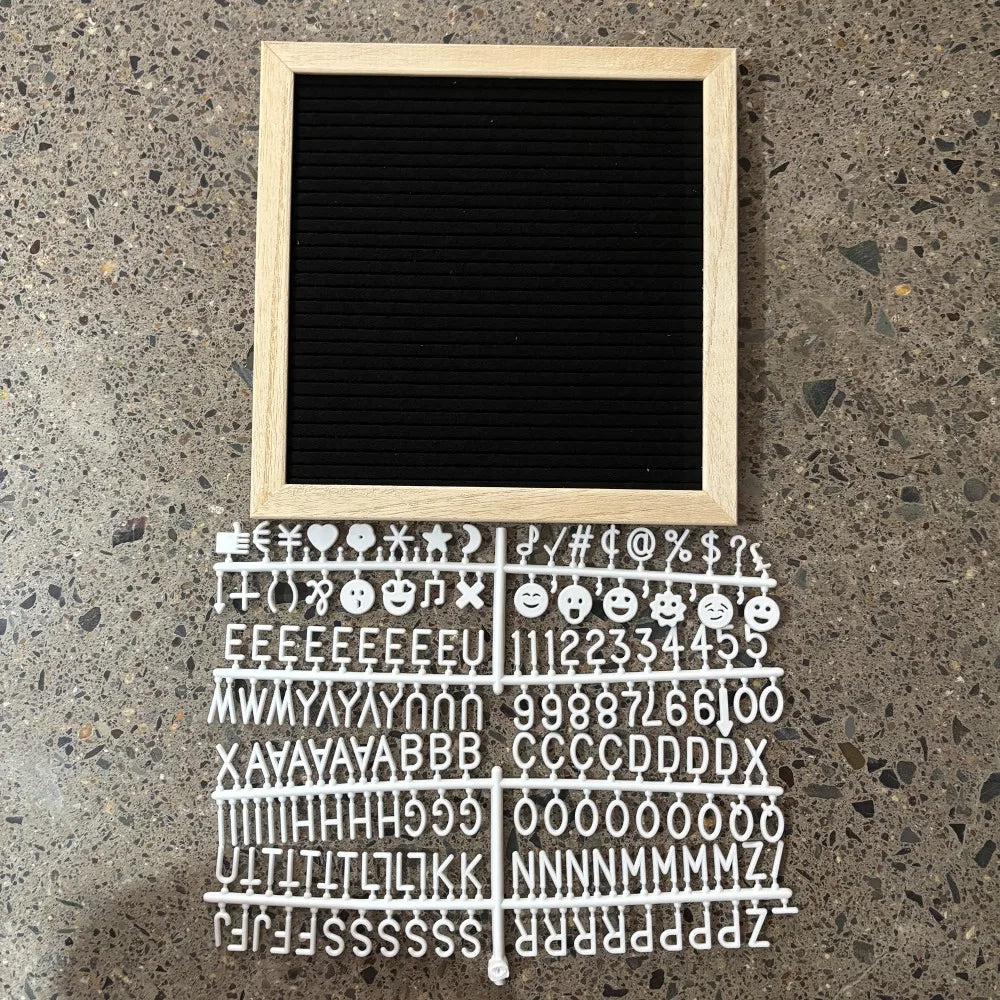 Felt Letter Board in black with white starter letters and symbols arranged beside the wooden frame.