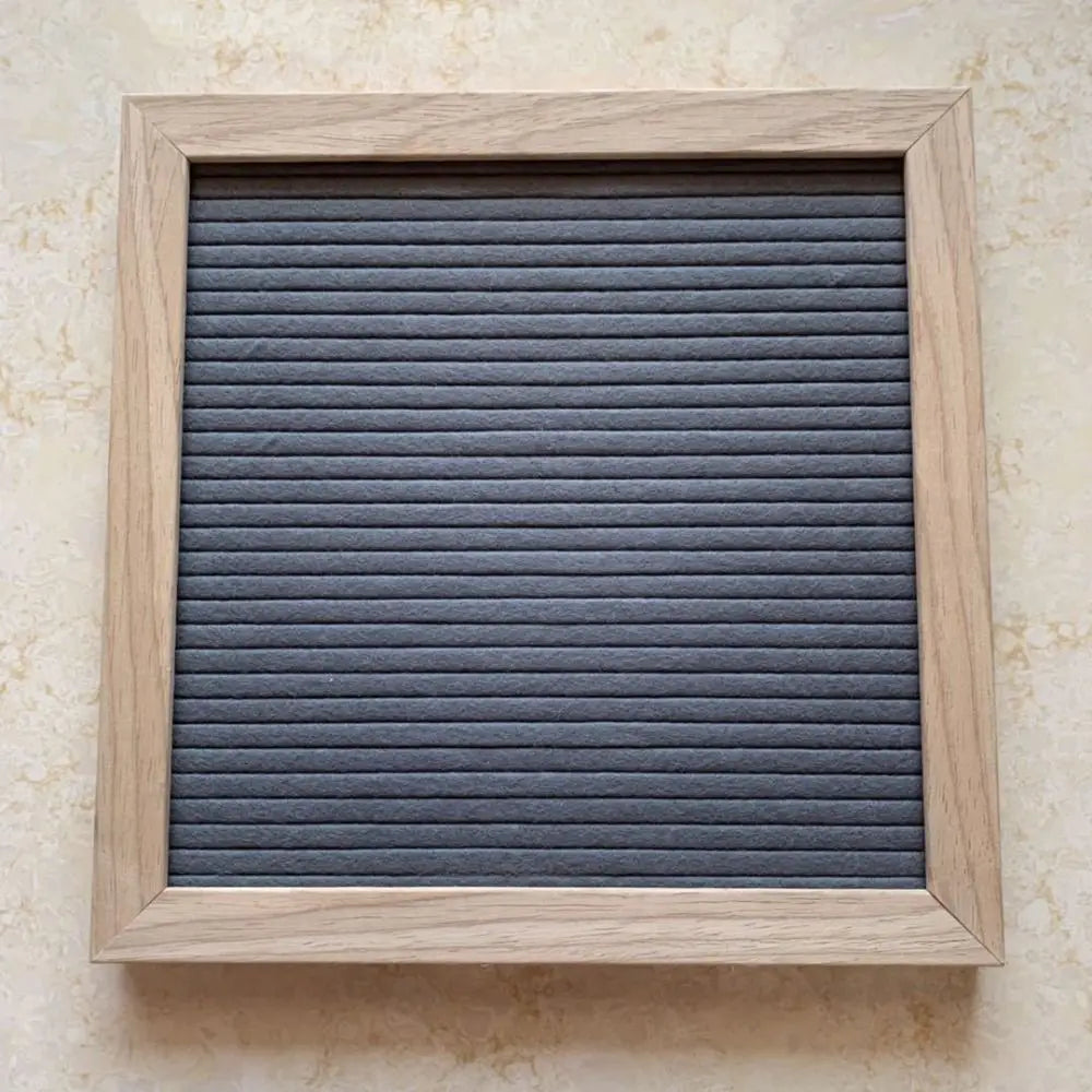 Felt Letter Board in gray mounted vertically on a wall inside its natural wooden frame.