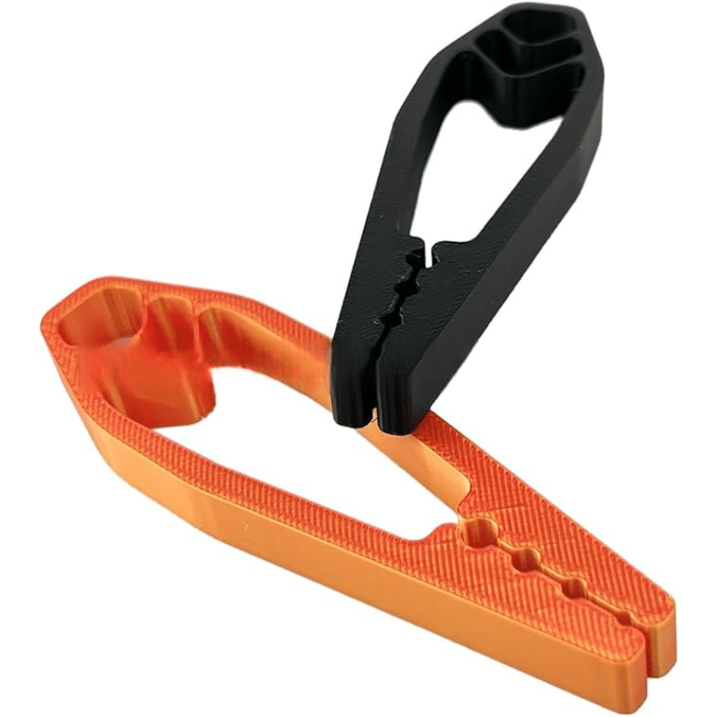 Black and orange plastic Finger-Safe Nail Holders showing stepped nail slots and textured grips
