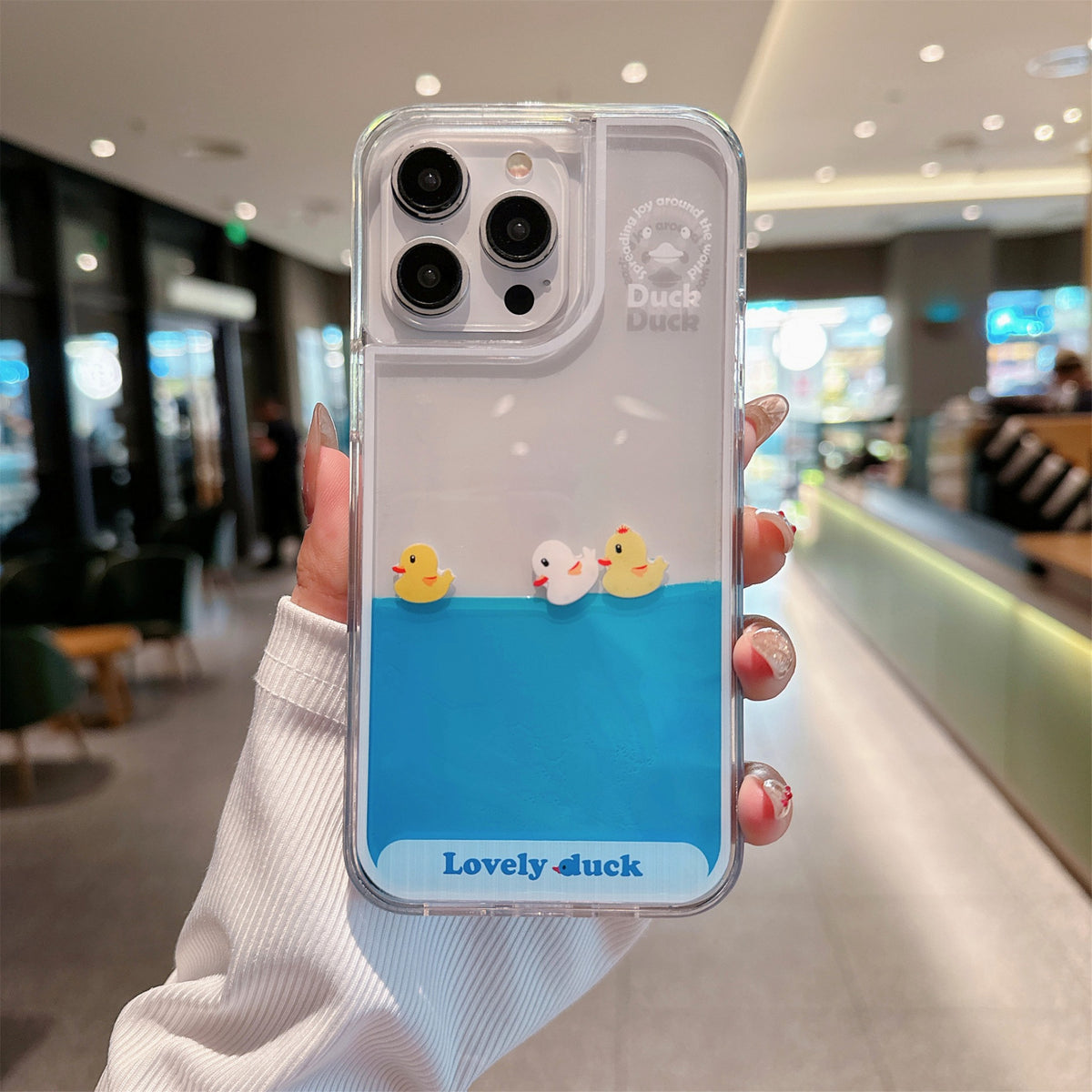 Floating Ducks Phone Case Three Ducks variant with a clear border and camera opening, held in one hand