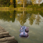 Floating Hippo Pond Decor front view of the hippo head floating beside a wooden dock with trees across the pond.
