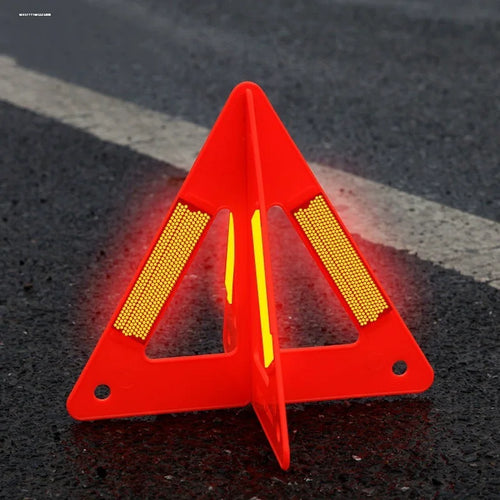 Foldable Warning Triangle standing open on dark asphalt, with a red body and bright reflective panels.