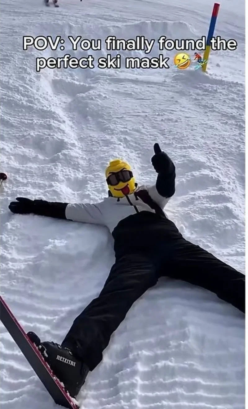 Tongue-out Funny Brickhead Ski Mask worn by a person lying in the snow and giving a thumbs-up