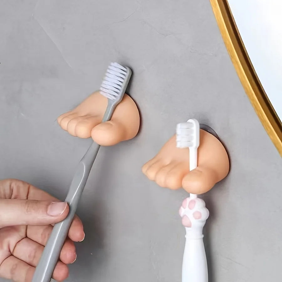 Funny Feet Toothbrush Holders shown close up with gray and white toothbrushes on a smooth wall