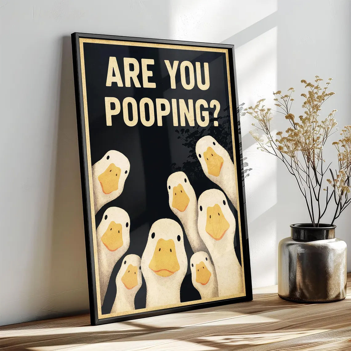 Funny Goose Bathroom Sign styled in a black frame on a wooden surface; print sold without frame