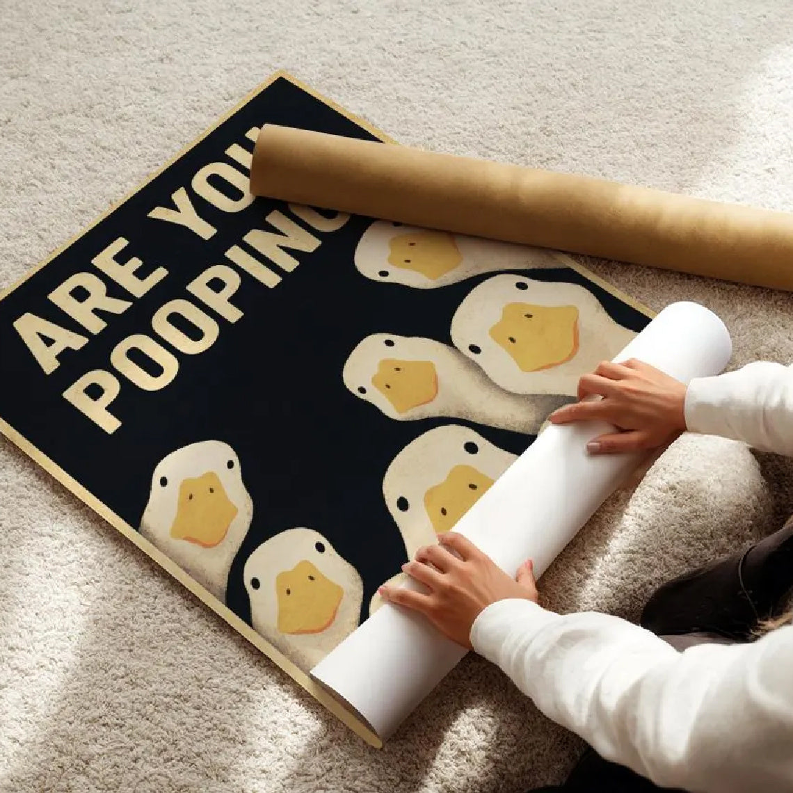 Funny Goose Bathroom Sign unframed canvas being unrolled on a light carpet beside a cardboard tube