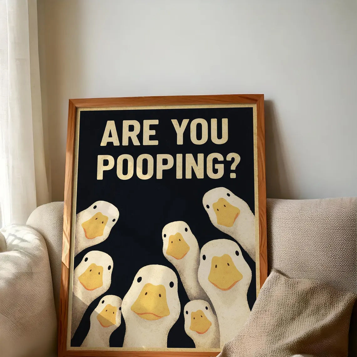 Funny Goose Bathroom Sign resting on a cream sofa in a wooden display frame; frame not included