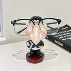 Funny Teacher Glasses Stand displaying black eyeglasses on a white desk beside a black book