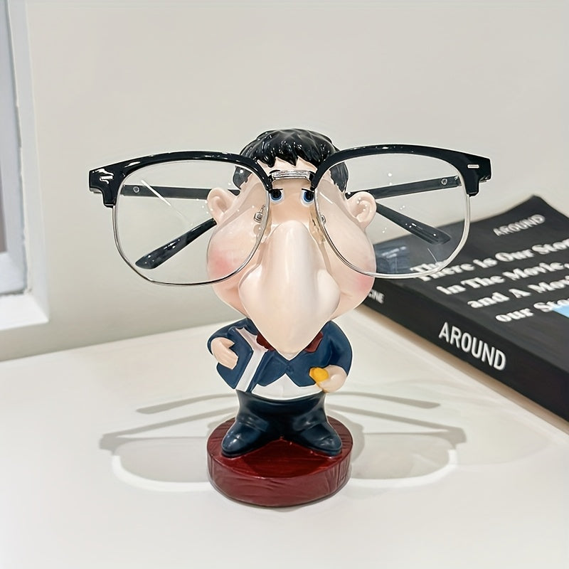 Funny Teacher Glasses Stand displaying black eyeglasses on a white desk beside a black book
