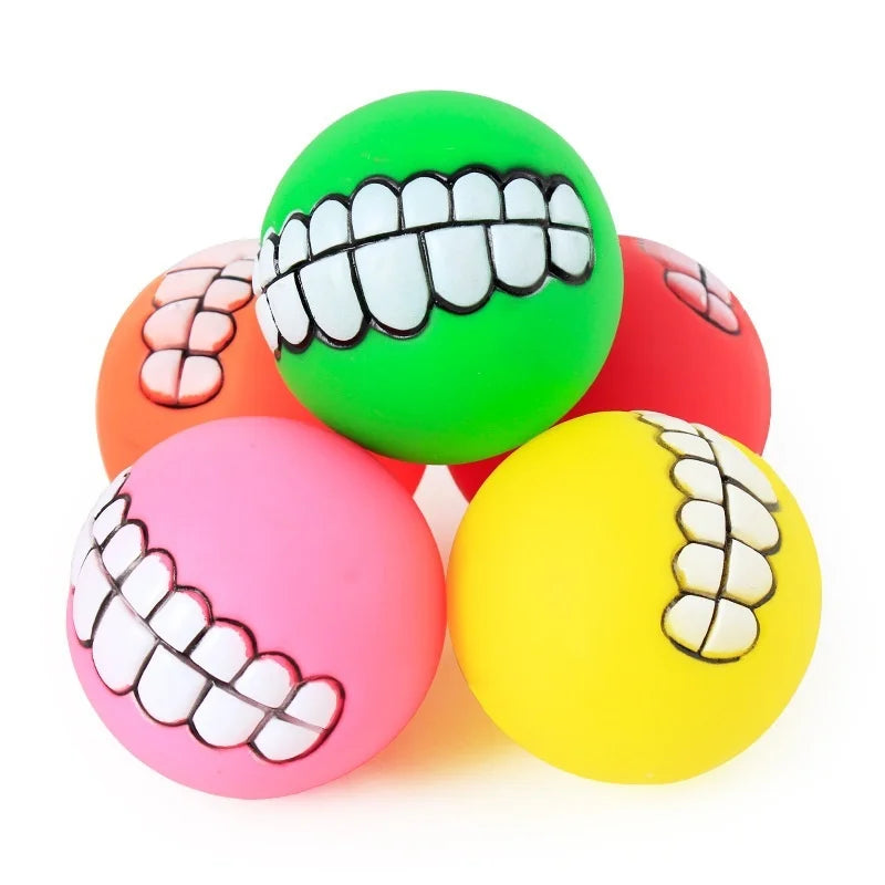 Funny Teeth Dog Balls stacked together, with a green grinning ball above pink and yellow balls.