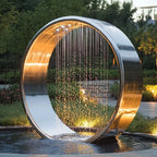 Garden Ring Waterfall Fountain at a garden angle, with warm light reflecting inside the broad polished silver ring