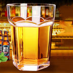 Giant Glass Drinking Cup faceted tumbler filled with an amber drink on a warm-toned bar display.
