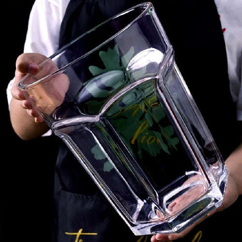 Giant Glass Drinking Cup empty oversized tumbler held at an angle with a hand supporting the base.