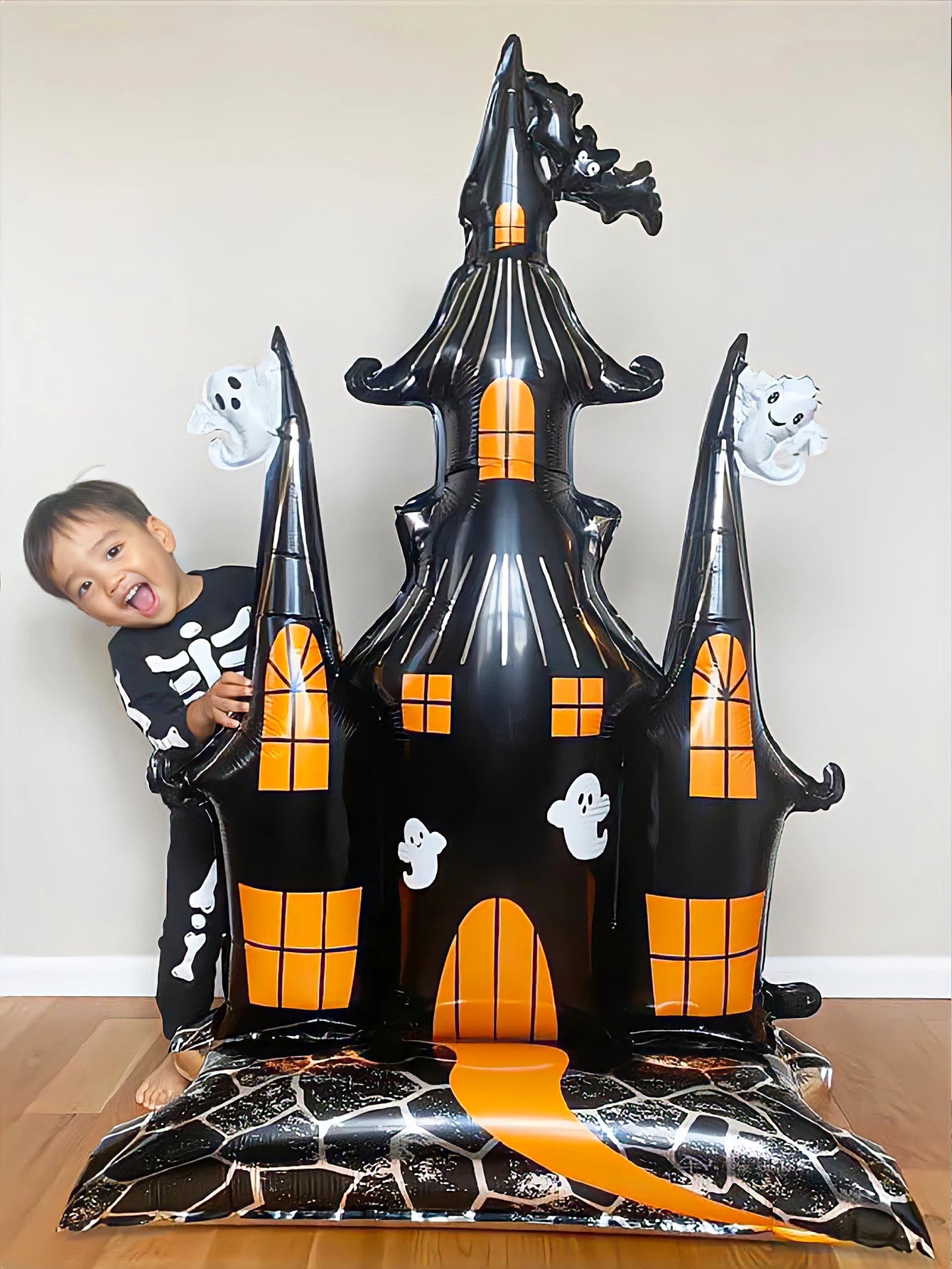 Giant Haunted House Balloon beside a child in a skeleton costume to demonstrate its oversized scale