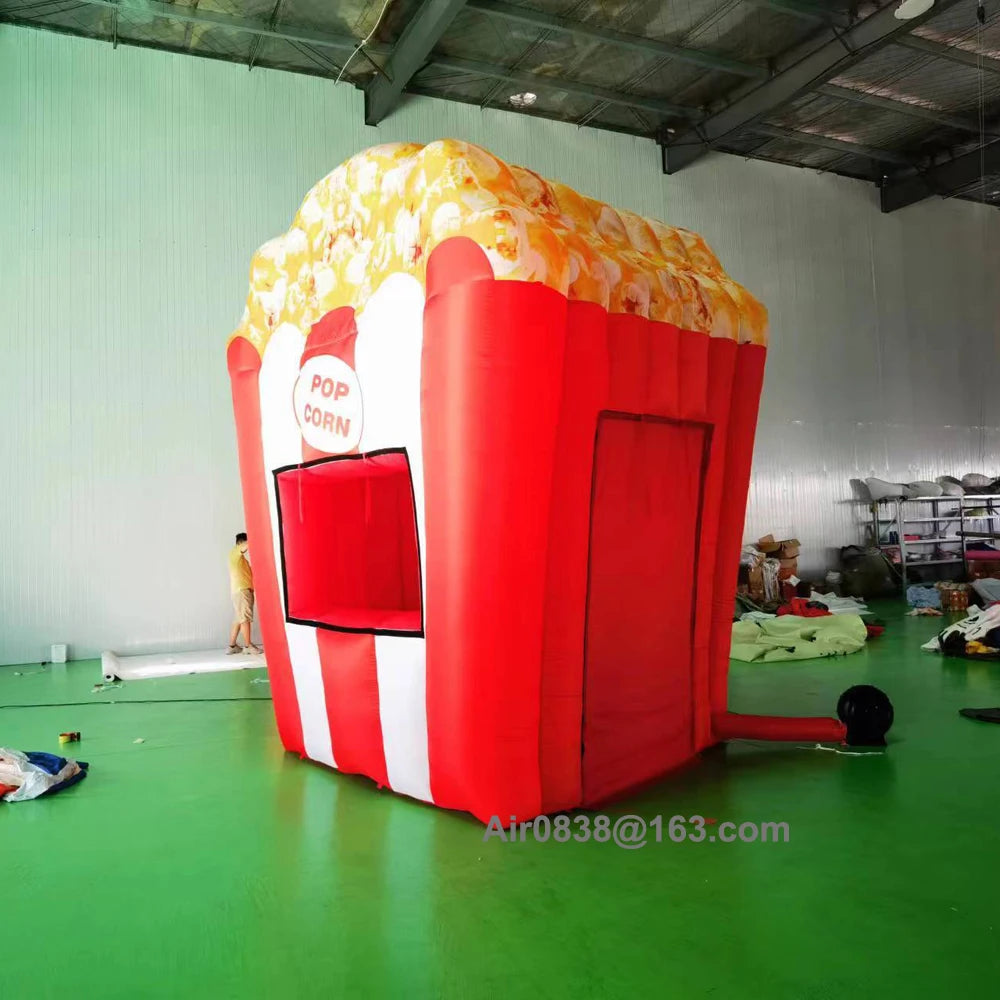 Three-quarter view of the inflatable popcorn stand showing the serving window, side door panel and connected blower.