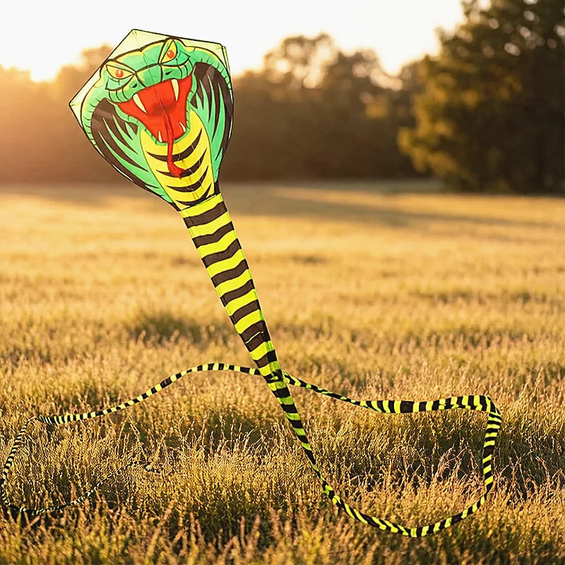 Giant Snake Kite spread across a golden field at sunset showing its cobra design and long striped tails