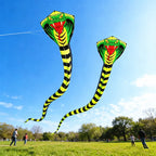 Two Giant Snake Kites flying together above a sunny public park with families in the distance