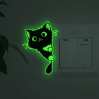Glow Guide Cat Sticker with bright green glow installed beside a wall switch near a houseplant