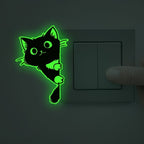 Glow Guide Cat Sticker glowing beside a dark light switch as a hand reaches toward it