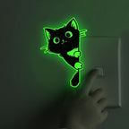 Glow Guide Cat Sticker glowing green beside a light switch during nighttime use
