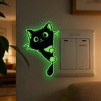 Glow Guide Cat Sticker glowing green beside a light switch in a warmly lit living room