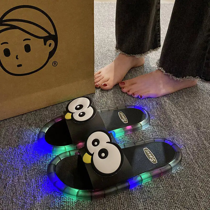 Black Glowing Googly Eye Slides with multicolor glowing soles on carpet beside a person's feet