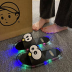 Black Glowing Googly Eye Slides with multicolor glowing soles on carpet beside a person's feet