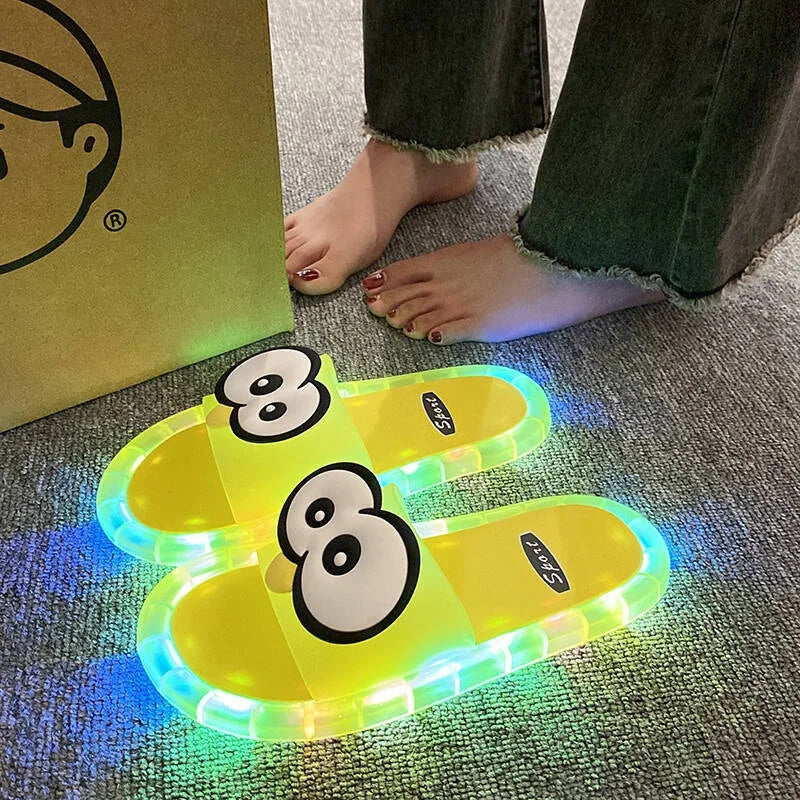 Yellow Glowing Googly Eye Slides with multicolor glowing soles on carpet beside a person's feet