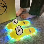 Yellow Glowing Googly Eye Slides with multicolor glowing soles on carpet beside a person's feet