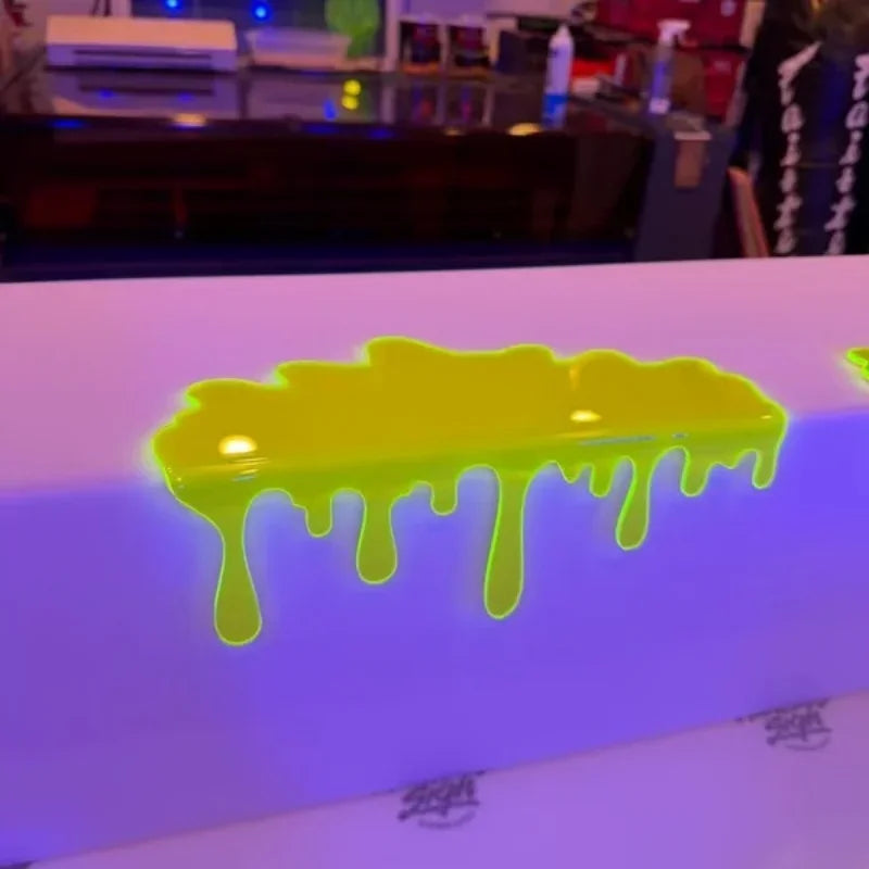 Glowing Slime Shelf Drips — Yellow-green shelf topper resting on a white display edge, viewed from above.