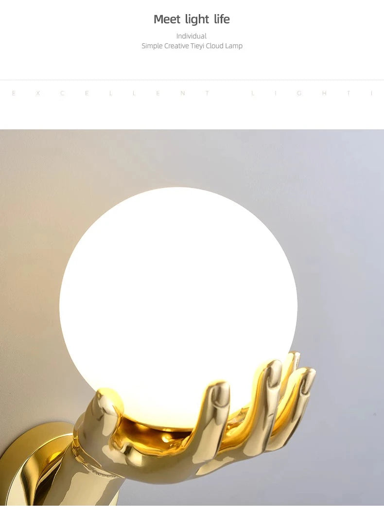 Golden Hand Wall Lamp — Close-up of the illuminated glass globe and gold fingers