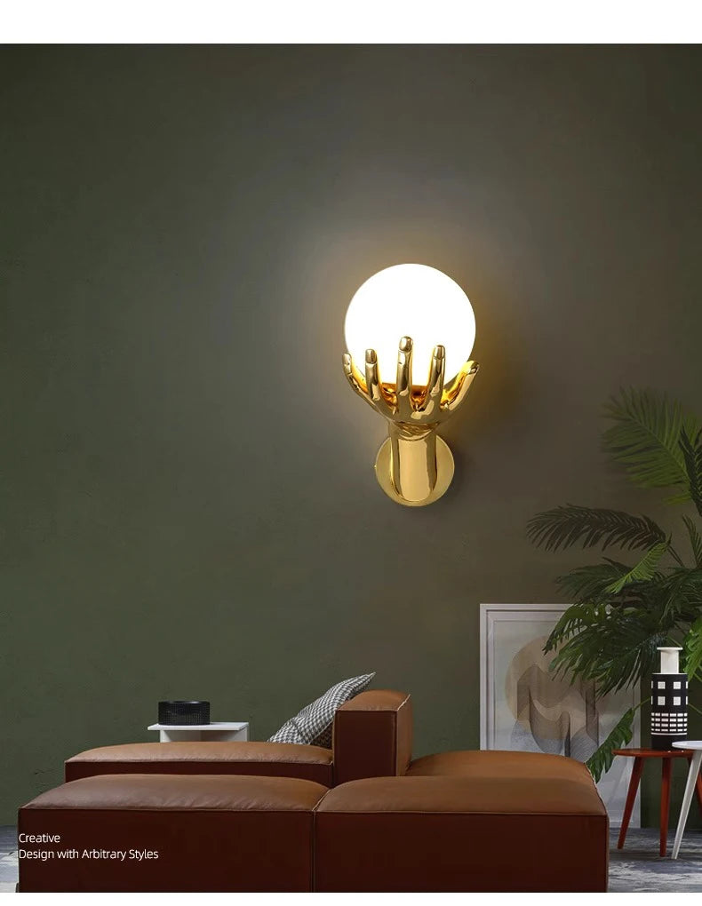 Golden Hand Wall Lamp — Front view of the glass shade on a green wall above a leather chaise