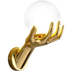 Golden Hand Wall Lamp — Close-up of the gold hand holding a smooth white glass globe