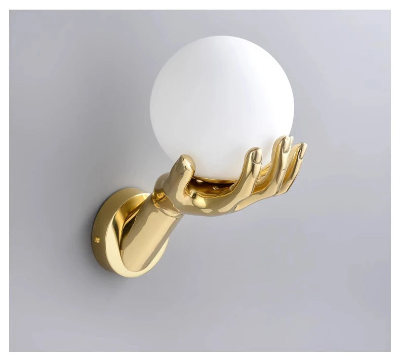 Golden Hand Wall Lamp — Unlit frosted glass globe cradled by the gold hand