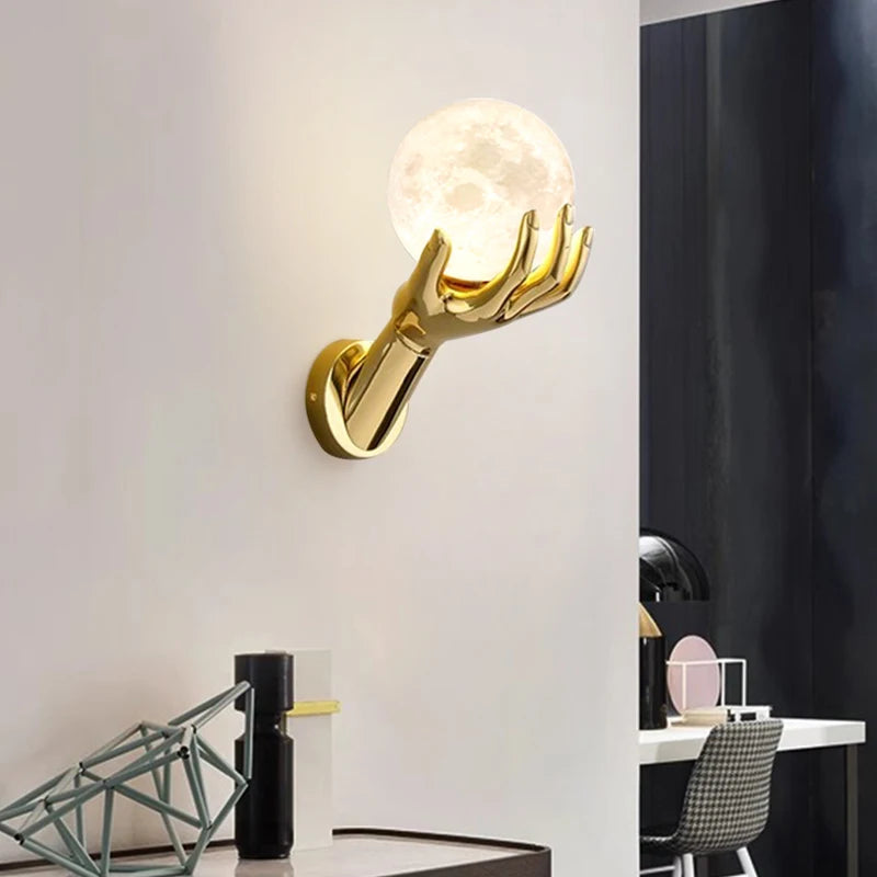 Golden Hand Wall Lamp — Moon shade glowing above a console beside a study area